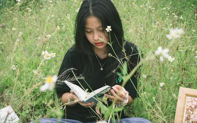 Student reading a book outdoors